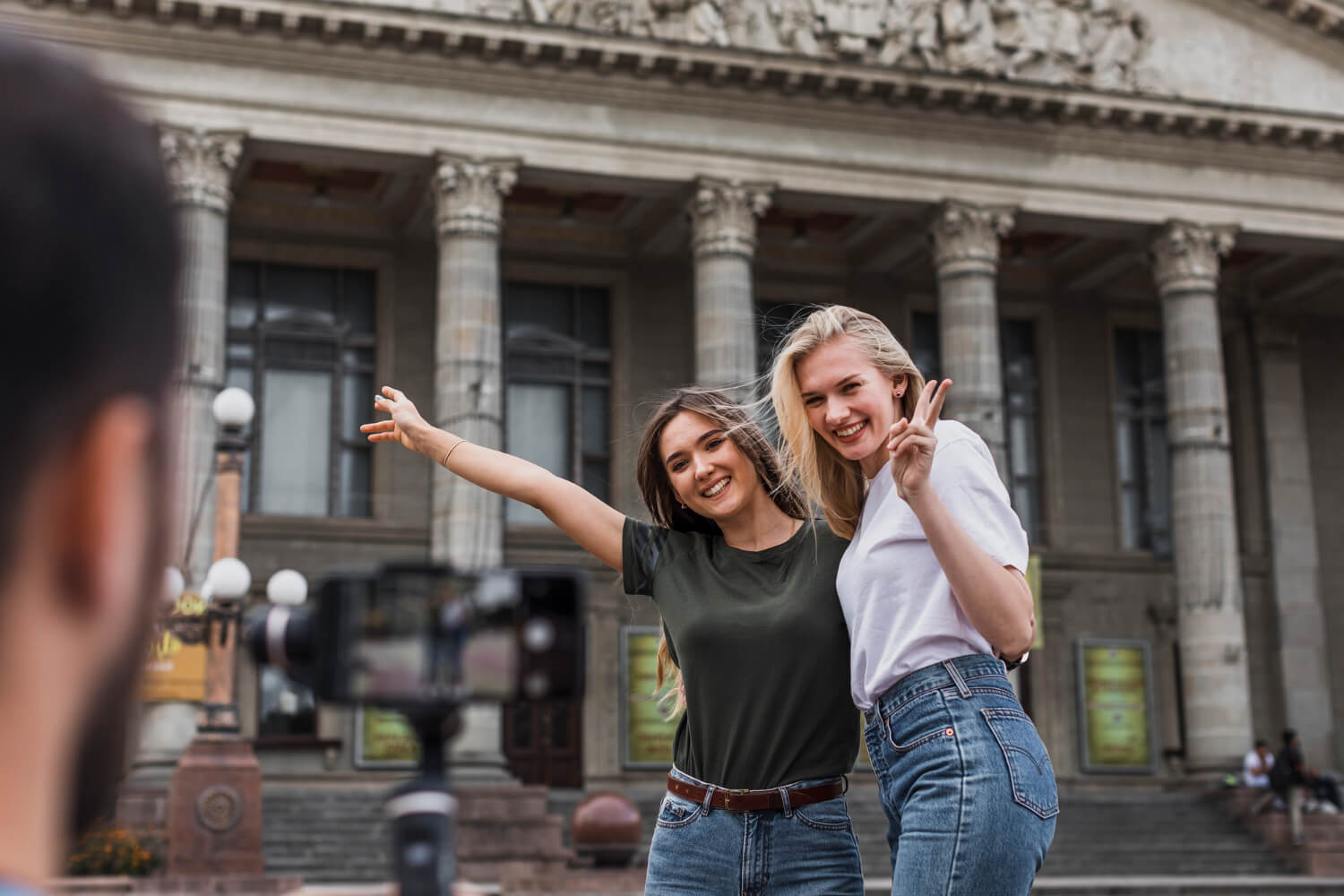 back-view-man-photographing-beautiful-women-with-phone